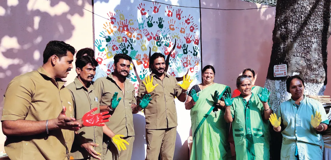 Sanitation workers pose outside the model chowki set up under Mission Garima in Kurla in Mumbai