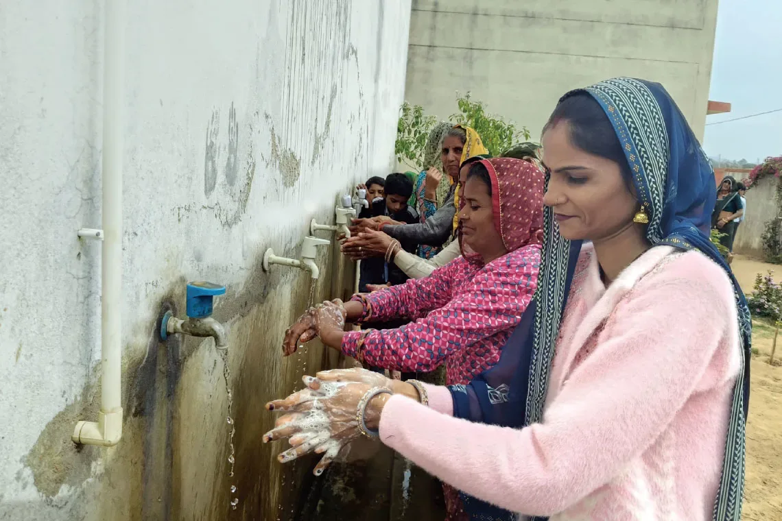 A cook and her helpers at a local school in Sapotara village in the Karauli district of Rajasthan wash their hands as part of a six-step process to promote hygiene