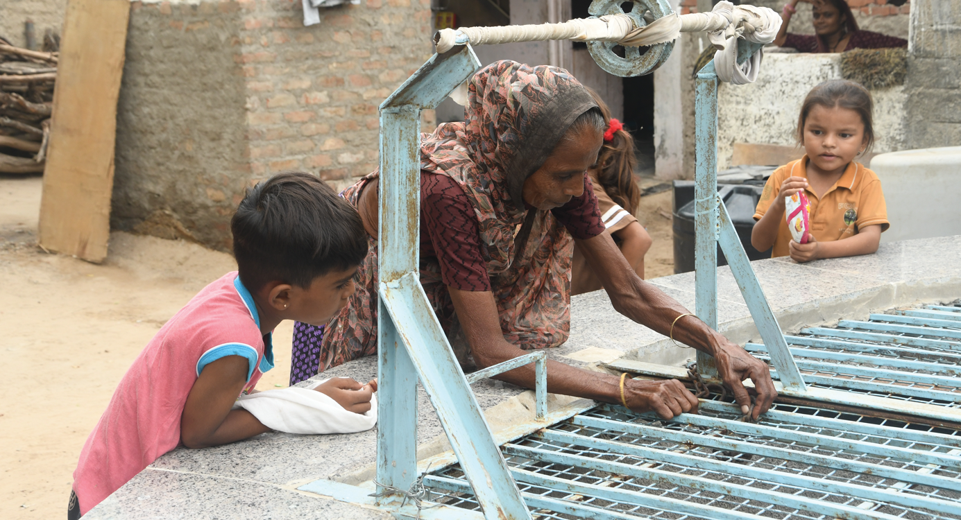 Taraben Thakur of the Shramjivi settlement in Patan checks the 80-year-old well in her neighbourhood that is being rejuvenated to provide an additional source of water