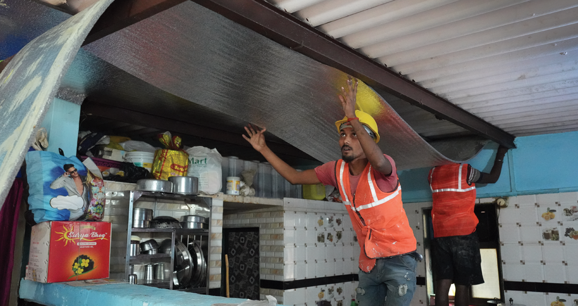 Workers secure alufoil panels in a house in Sai Sadan in Mira Bhayander to reduce indoor temperature