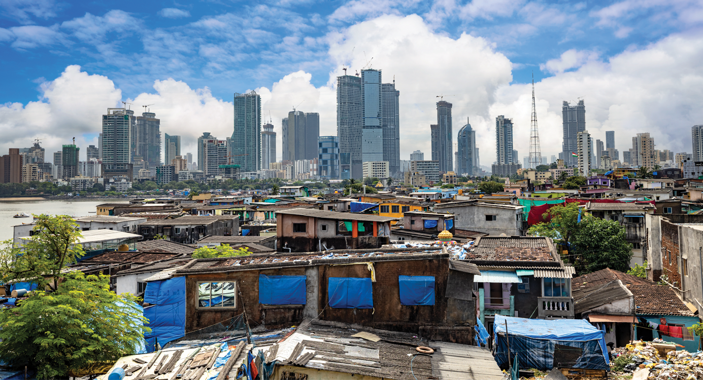 A slum in Mumbai set against the backdrop of skyscrapers; slums are not just a housing problem, says Dr Kundu